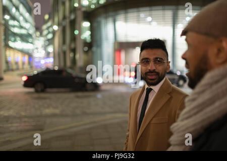 Businessmen talking on city street at night Stock Photo