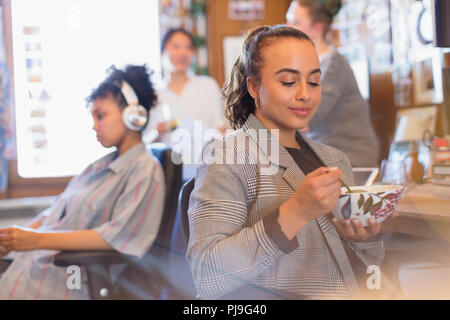 Creative businesswoman eating soup in office