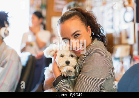 Portrait happy businesswoman with cute dog in office Stock Photo