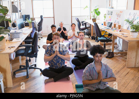 Creative business people meditating in office Stock Photo