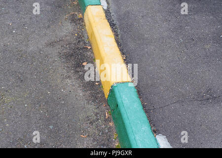 old green and yellow painted kerbstone on sidewalk Stock Photo