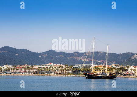 Mediterranean resort of Marmasis along the Turkish Riviera (also known as the Turquoise Coast) with a busy, pebbly beach and long seafront promenade. Stock Photo