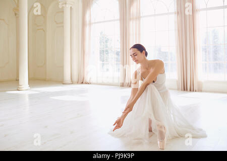 A ballerina in white clothes in a white studio. Stock Photo