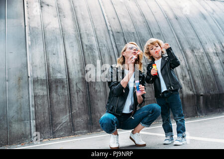 mother and son blowing soap bubbles on street Stock Photo