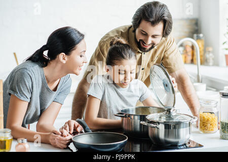 smiling young family cooking together at kitchen Stock Photo