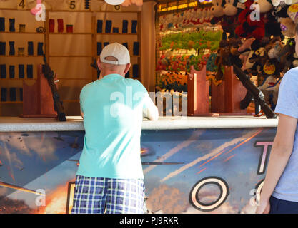 A man shoots a rifle in the prize dash, the view from the back, the amusement Park in the summer Stock Photo