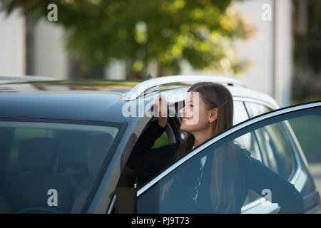 young woman opens door and gets in the car Stock Photo