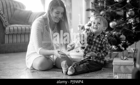 Black and white image of cheerful laughing boy throwing confetti in living room on Christmas morning Stock Photo