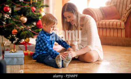 Cute little boy with mother on Christmas morning sitting at living room Stock Photo