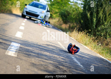 Close-up of a bicycling helmet fallen on the asphalt next to a bicycle after car accident Stock Photo