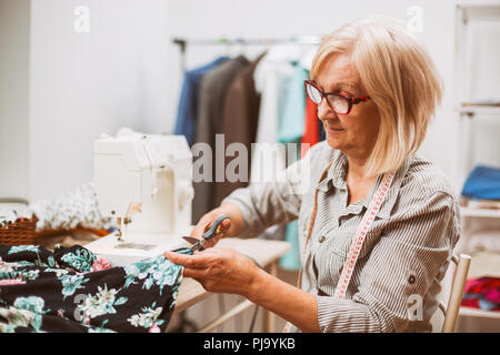 Adult woman is sewing in her studio. Stock Photo