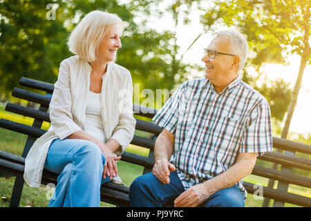 Two happy seniors are sitting and talking in park. Stock Photo