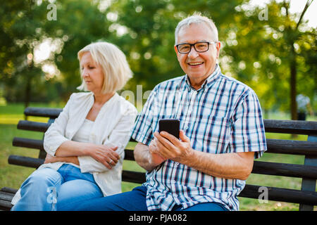 Senior woman is angry while her man is messaging on phone. Stock Photo