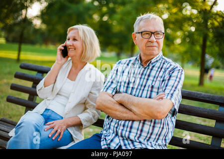Senior man is angry while his woman is talking on phone. Stock Photo