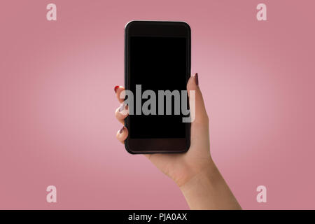 women Hand holding black smartphone with black screen on pink background Stock Photo