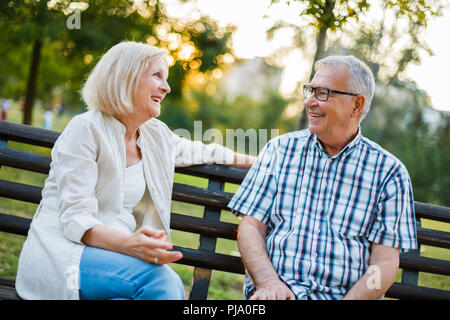 Two happy seniors are sitting and talking in park. Stock Photo