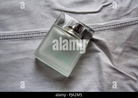 Rectangular perfume bottle with frosted glass effect on light grey jeans Stock Photo