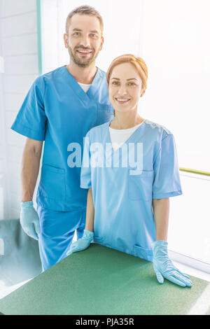 smiling two veterinarians standing in uniform and looking at camera at veterinary clinic Stock Photo