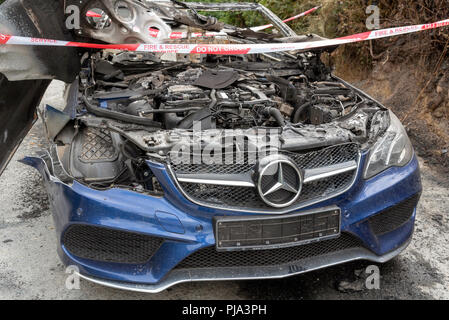 Fire damaged car showing the Fire & Rescue Service Do Not Cross plastic ribbon. Stock Photo