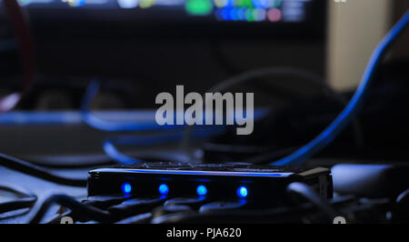 Close-up of black color Universal Serial Bus (USB) hub device with the number indicator light ON, blur black background Stock Photo