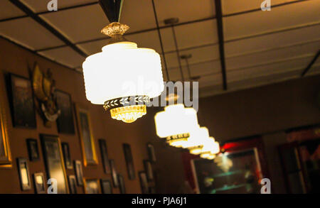 Close-up of lights lined up on the roof in a room filled with frescoes and photos, with a blurred background adding depth and ambiance Stock Photo