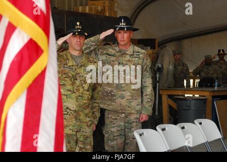 ERBIL, Iraq – U.S. Army 7th Squadron, 17th Cavalry Regiment Operations Officer Maj. Ty Huffman (left) and Standardization Officer Chief Warrant Officer 5 Steve Crandall render a salute while the National Anthem plays prior to a transfer of authority ceremony July 2, 2018. The ceremony signified the assumption of command of the mission to provide enabling support to Coalition and partner forces in the defeat-ISIS mission in support of Operation Inherent Resolve. Stock Photo