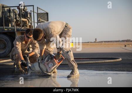 UNDISCLOSED LOCATION, MIDDLE EAST – U.S. Marine Corps Cpl. Joshua Garza (left), a small arms repair technician and LCpl Connor Reid (right), a combat engineer with Marine Wing Support Squadron 371 attached to Special Purpose Marine Air-Ground Task Force, Crisis Response-Central Command cut through pavement while repairing a damaged airfield  July 3, 2018. The Airfield Damage Repair team ensures runways are safe to conduct flight operations throughout the region. Stock Photo