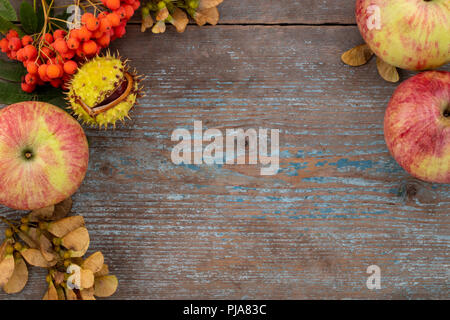 Autumn background from fallen leaves and fruits with vintage place setting on old wooden table. Thanksgiving day concept. Stock Photo