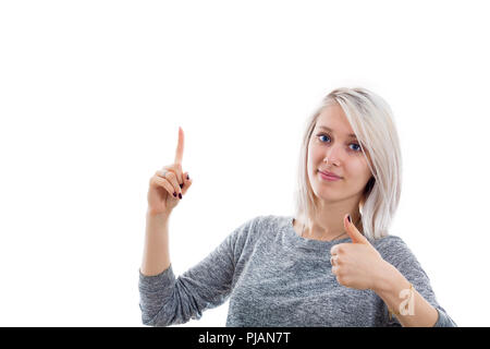 Enthusiastic young woman showing thumb up gesture with one hand and pointing finger up with another. Stock Photo