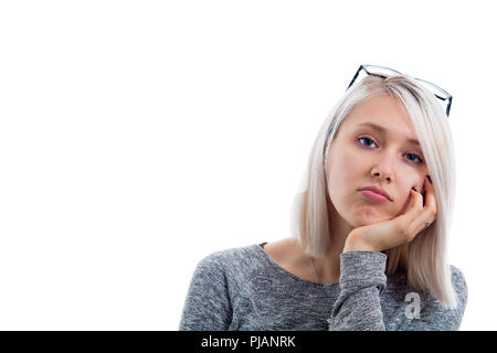 Portrait of bored annoyed beautiful girl with straight blonde hair looking at camera with blue eyes holding hand under chin, wearing trendy eyewear on Stock Photo