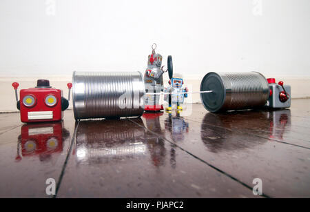 concept phone line being cut of with retro robots on a wooden floor Stock Photo