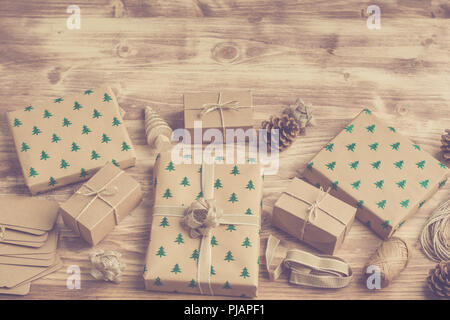 Toned photo of brown boxed Christmas presents boxes with embossed Christmas trees on the grey wooden background, copy space for text Stock Photo