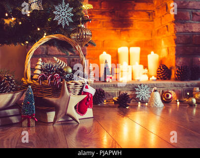 Christmas setting background: wooden star in front of decorated Christmas tree, pine cones in the basket, wooden trees, with fireplace on the backgrou Stock Photo