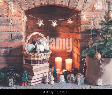 Christmas decorations in the basket, the fireplace on the background with candles an baubles, selective focus Stock Photo