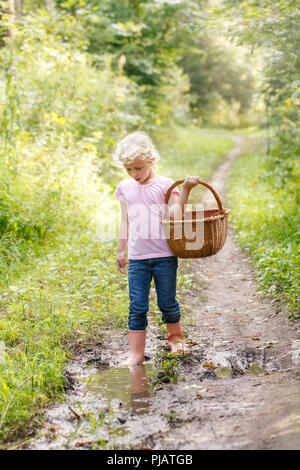 Cute adorable white Caucasian blonde preschool little girl picking fresh edible mushrooms in wicker basket. Autumn fall activity hobby concept. Stock Photo