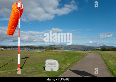 Dayglo orange wind sock, and memorial stone at Millport Helicopter Landing Site (helipad), run by the Scottish Ambulance Service on the Isle of Cumbra Stock Photo