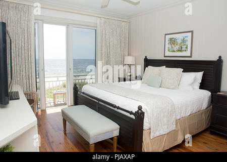 An interior shot of a bedroom with a balcony that overlooks the ocean. Stock Photo