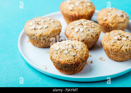 Healthy vegan oat muffins, apple and banana cakes with sour cream on a white plate. Blue background. Stock Photo