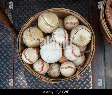 A basket of old weathered baseballs sitting outside on the street Stock Photo