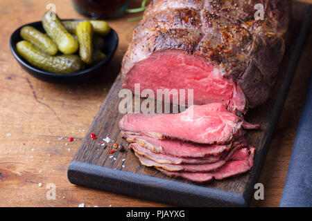 Roast beef on cutting board. Wooden background. Stock Photo