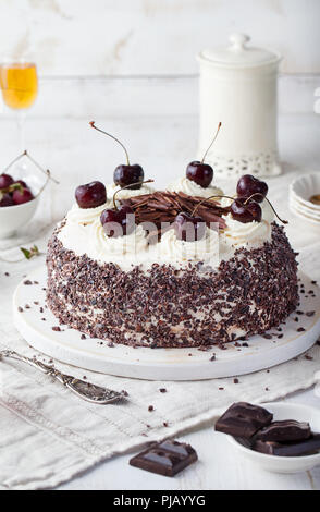 Black forest cake, Schwarzwald pie, dark chocolate and cherry dessert on a white wooden cutting board. Stock Photo
