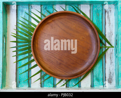 Wooden plate with palm leaf on colorful background. Copy space. Top view. Stock Photo