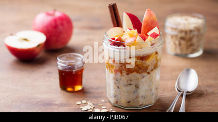 Overnight oats, bircher muesli with apple, cinnamon and honey. Wooden background. Stock Photo