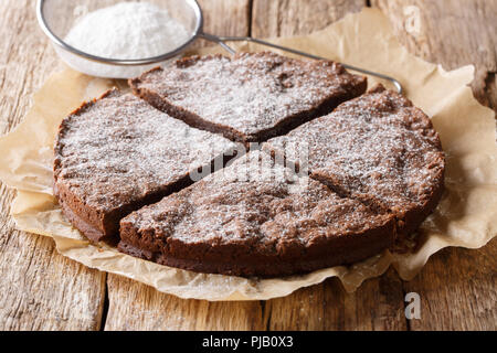 home-made fresh Swedish dessert: kladdkaka chocolate sticky cake with powdered sugar close-up on the table. Horizontal