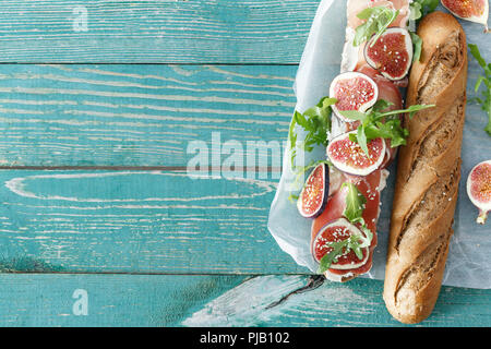 Sandwich with prosciutto, mascarpone cheese and figs on wooden table with border top view Stock Photo