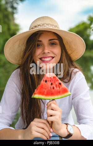 young beautiful woman eating watermelon by the river Stock Photo