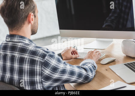 back view of young programmer using desktop computer at workplace Stock Photo