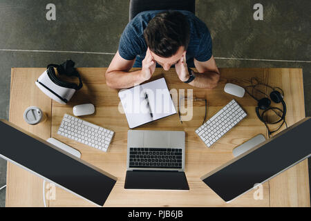 overhead view view of focused young man working with laptop and desktop computers Stock Photo