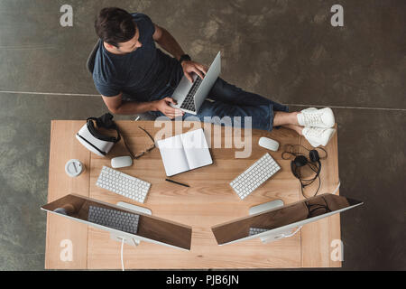 overhead view of young man using laptop and desktop computers at workplace Stock Photo