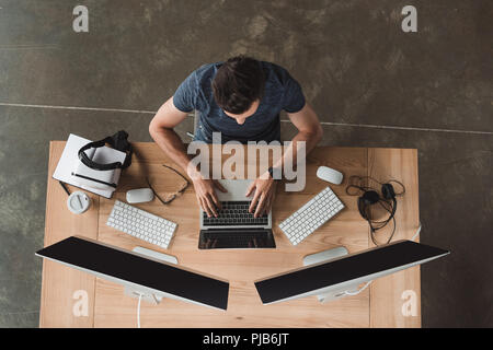 overhead view of young programmer using laptop and desktop computers at workplace Stock Photo